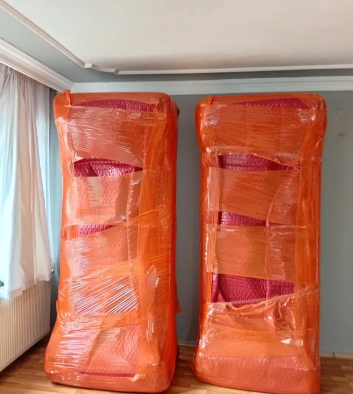 Turuncu streç ve kırmızı naylonla paketlenmiş iki koltuk
