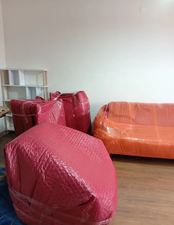 Kırmızı baloncuklu naylonla paketlenmiş koltuklar ve turuncu streçli kanepe